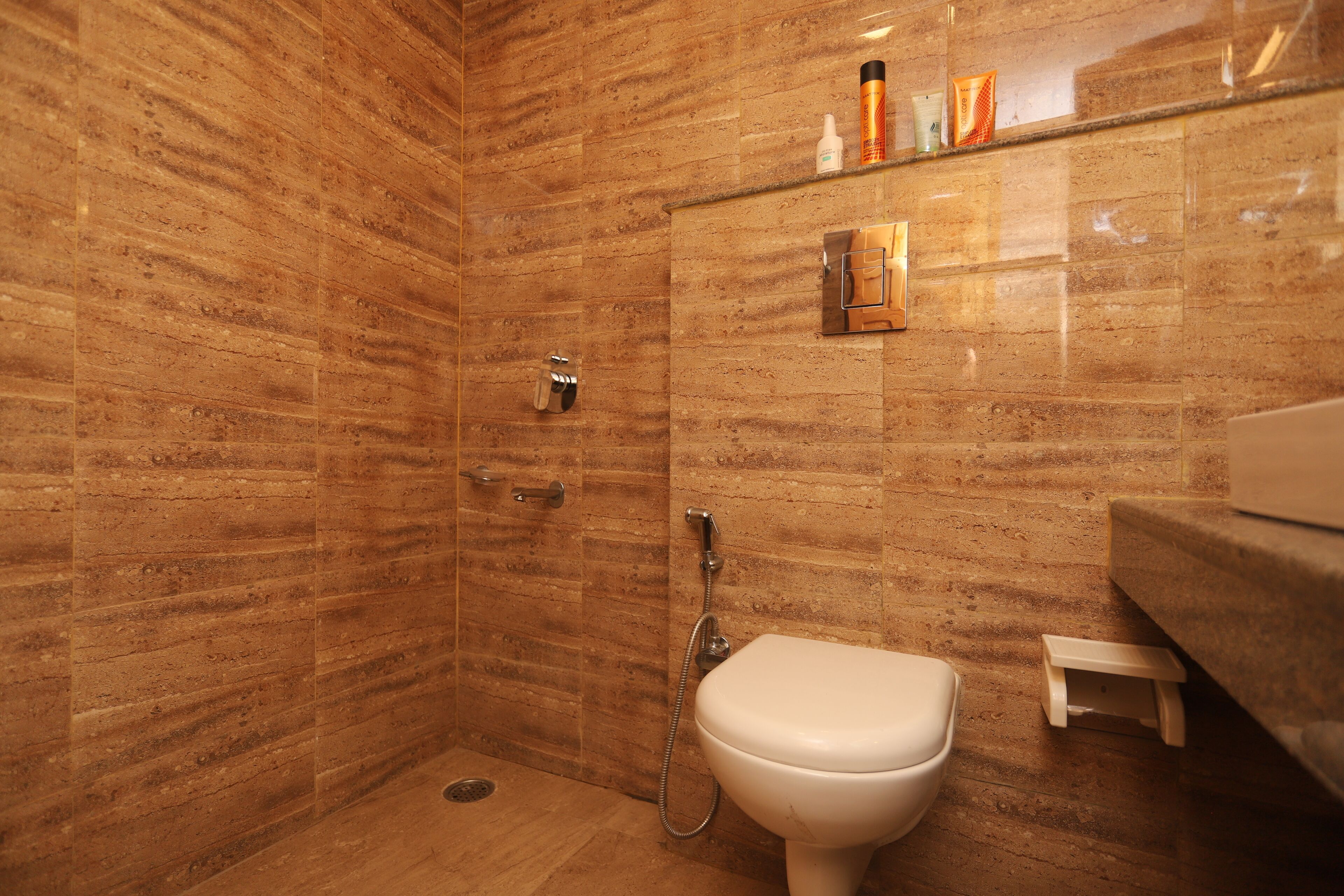 Ein Badezimmer mit Dusche, Toilette und Ablage für Kosmetikartikel.