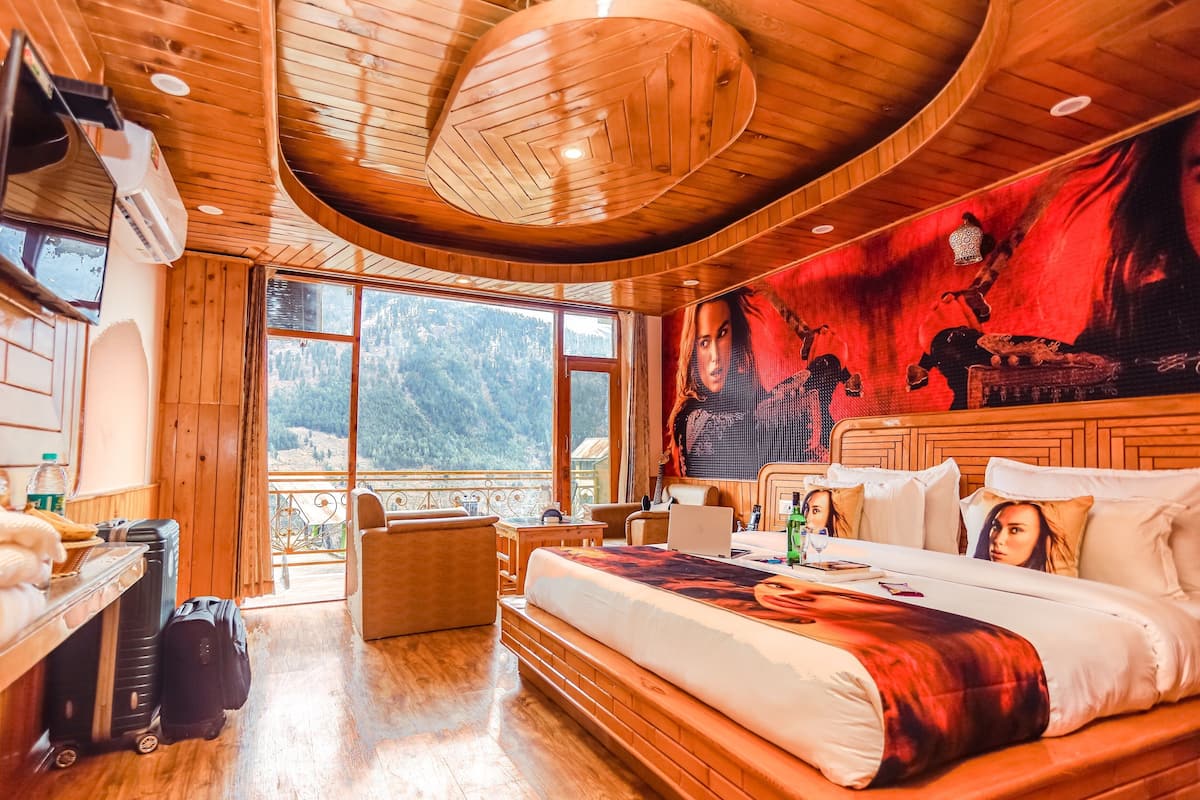A wooden cabin bedroom with a large bed, a desk, and a chair.