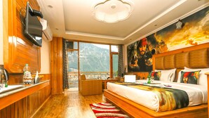 Une chambre spacieuse avec un grand lit, une télévision et une vue magnifique sur les montagnes, visible par les fenêtres.