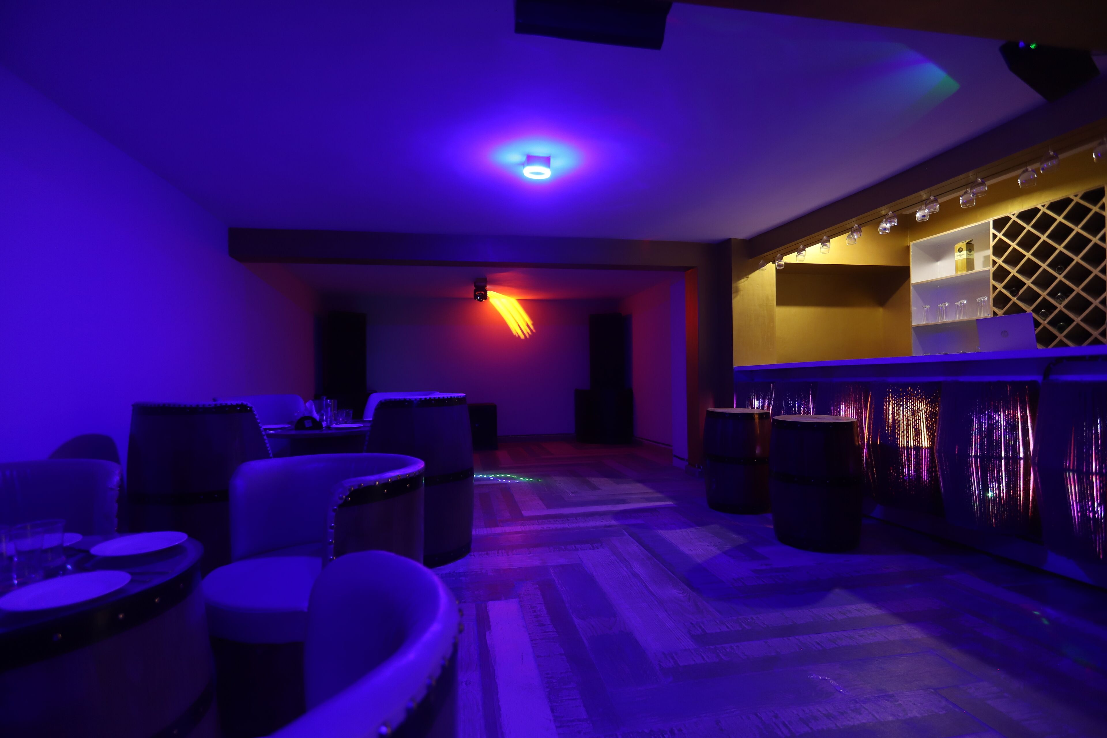 A dimly lit room with a bar area, seating, and a patterned floor.