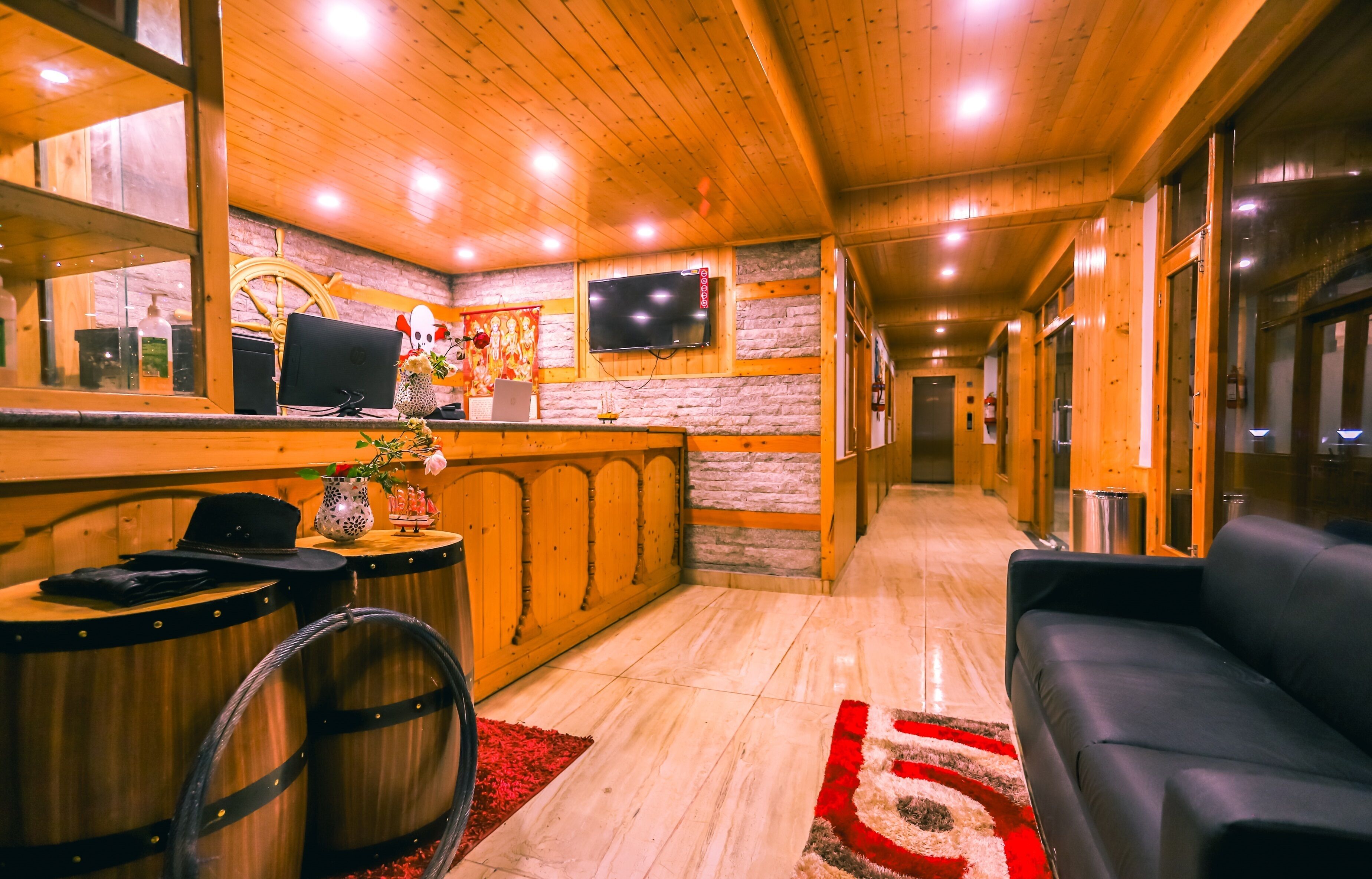A wooden interior with a reception desk, a TV, and a sofa.