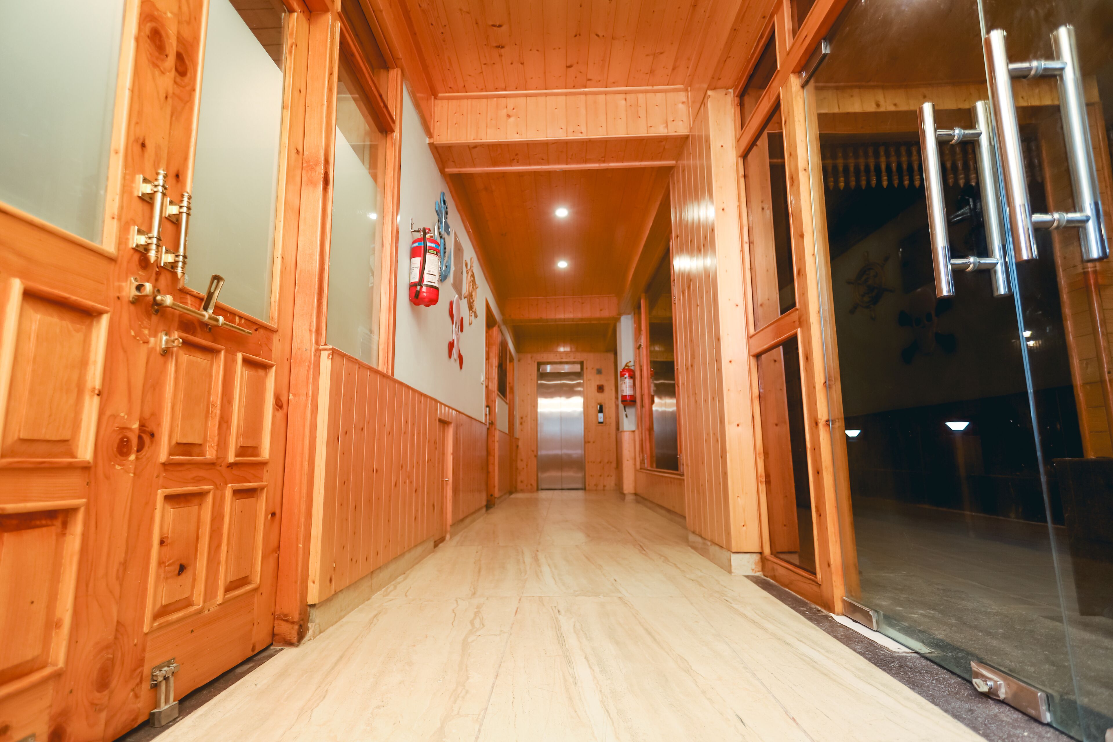 Un couloir en bois, doté d’un plancher ciré, de portes en bois et d’un extincteur fixé au mur.