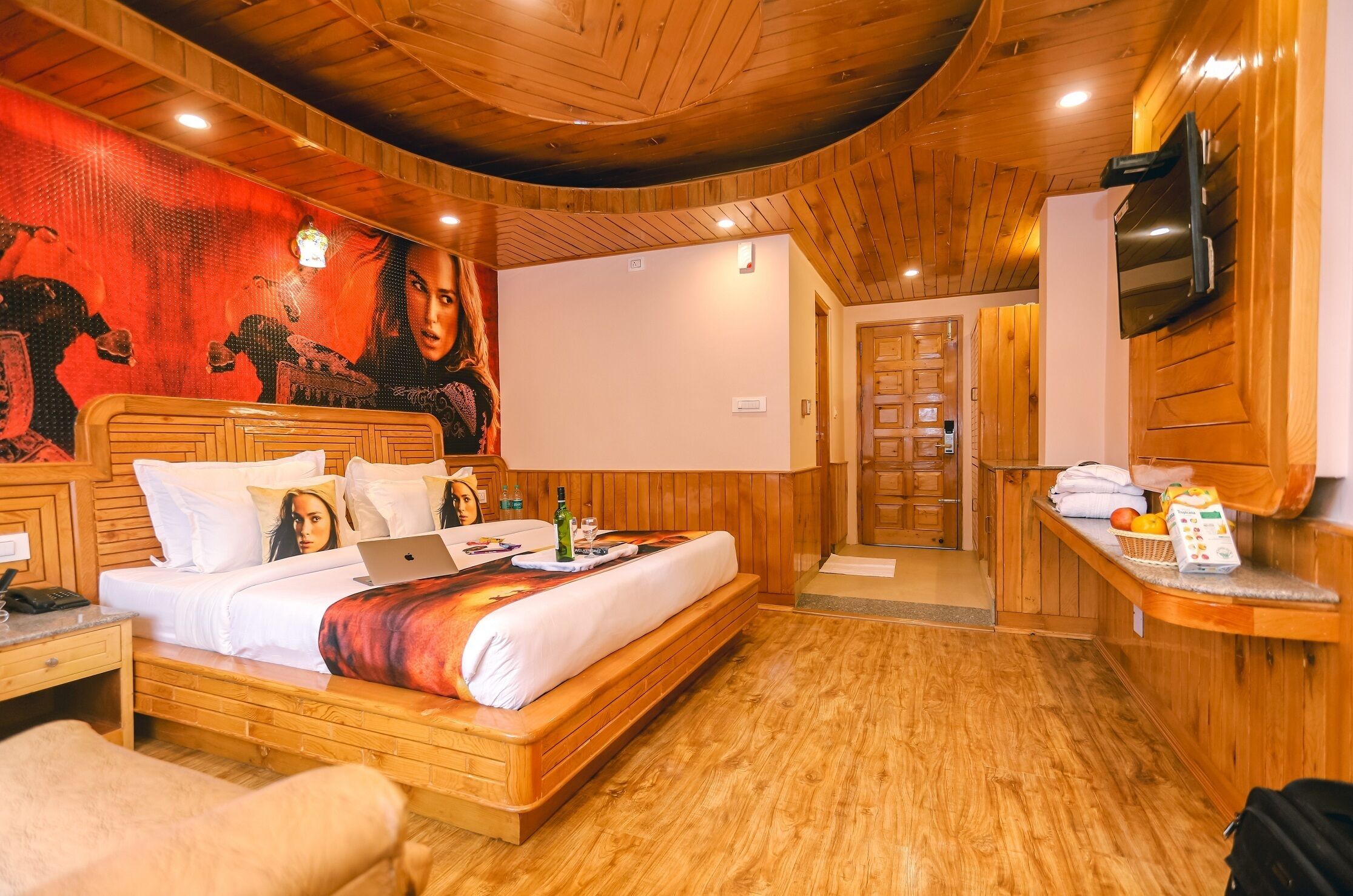 A wooden-themed hotel room with a bed, a TV, and a breakfast bar.