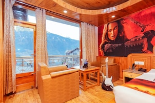 A cozy room with a wooden interior, a bed, a guitar, and a table with a bottle.