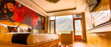 Un dormitorio con una cama grande, un televisor montado en la pared y vistas al exterior a través de la ventana.
