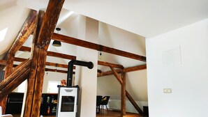 A spacious loft with exposed wooden beams, a built-in wood stove, and a view of the outdoors. - Large vacation home on the Aschberg, great view, terrace & large garden 6+2  (Klingenthal)