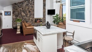 Een moderne keuken met een stenen accentmuur, een inbouw-kookeiland en een groot raam.