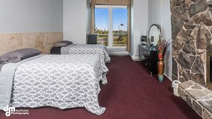 Een slaapkamer met twee bedden, een stenen openhaard en uitzicht op de omgeving.
