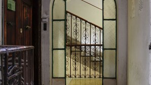 Un arco de entrada con una reja metálica, una puerta de madera a la izquierda y un piso de baldosas.