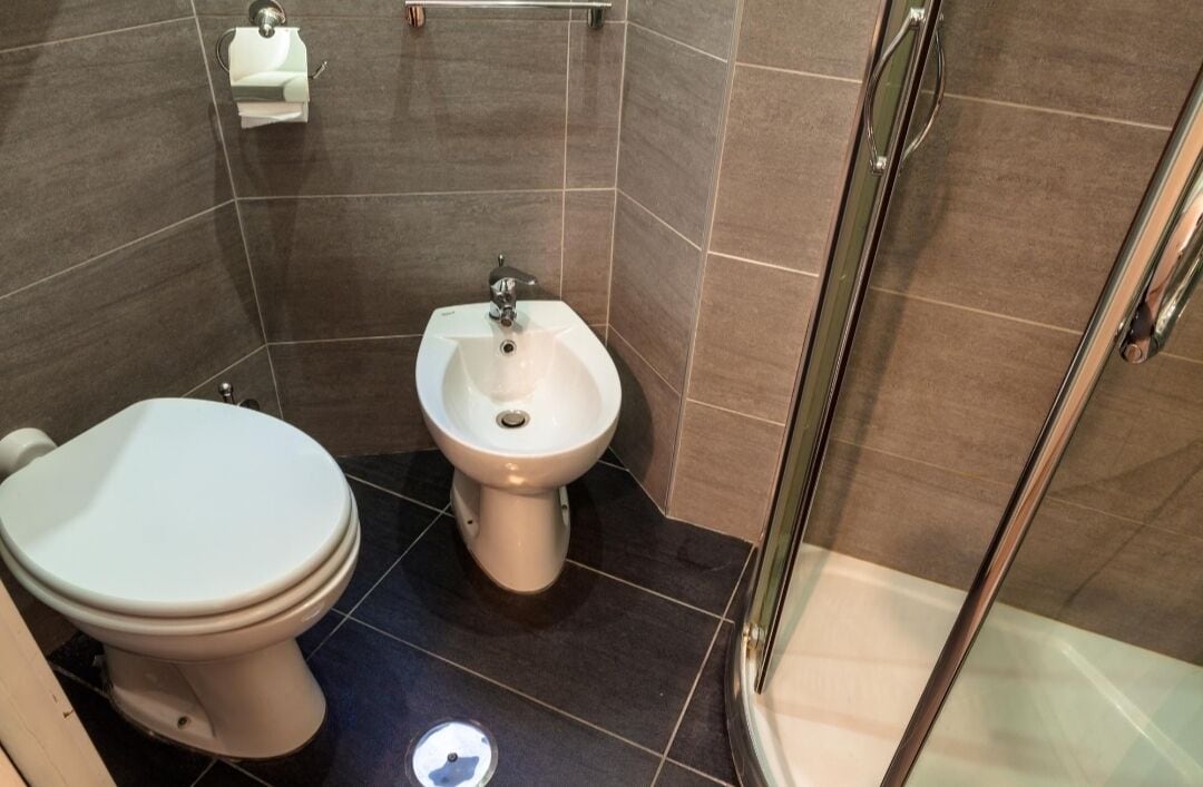Et badeværelse med toilet, bidet og brusekabine i glas.