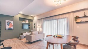 Ein modernes Wohnzimmer mit einer Couch, einem Esstisch und einem Fernseher.