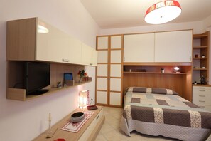 Une chambre à coucher comprenant un lit, une télévision, un bureau avec une lampe et une armoire.