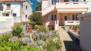 Un edificio residenziale con un giardino antistante, caratterizzato da un vialetto lastricato e diverse piante.