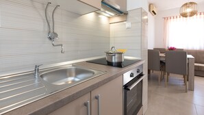 Una cucina moderna con un lavello doppio, elettrodomestici in acciaio inossidabile e un'area pranzo con tavolo e sedie.