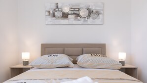 Un letto rifatto con due cuscini etichettati "Boss", un comodino con una lampada e un'opera d'arte astratta appesa al muro.