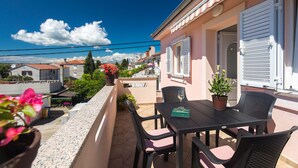 Un balcone con tavolo e sedie, un vaso con una pianta e vista sul quartiere.