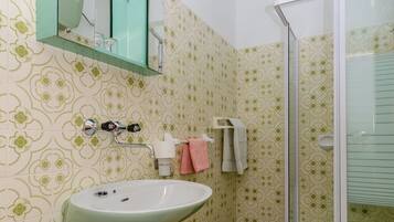 Een badkamer met een groen wastafel, toilet, douche en spiegel.