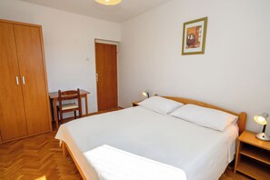 Une chambre à coucher comprenant un lit, un bureau, une chaise et une table de chevet avec une lampe.