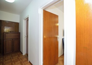 Un pasillo con un armario de madera, una puerta blanca y otra de madera.