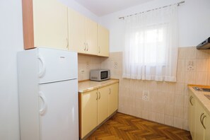 Une cuisine de taille réduite, avec un réfrigérateur blanc, un four à micro-ondes et des armoires en bois.
