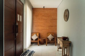 A hallway with a wooden door, two wooden chairs with cushions, a small wooden table with a bowl, and a pair of slippers on the floor. - Radiance Hill View 10BR Villa with a Private heated swimming Pool (Cimenyan)