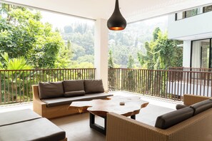 A balcony with a sofa, a table, and a hanging light fixture. - Radiance Hill View 10BR Villa with a Private heated swimming Pool (Cimenyan)