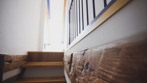 Un escalier en bois avec une rampe blanche, et une fenêtre visible au fond.