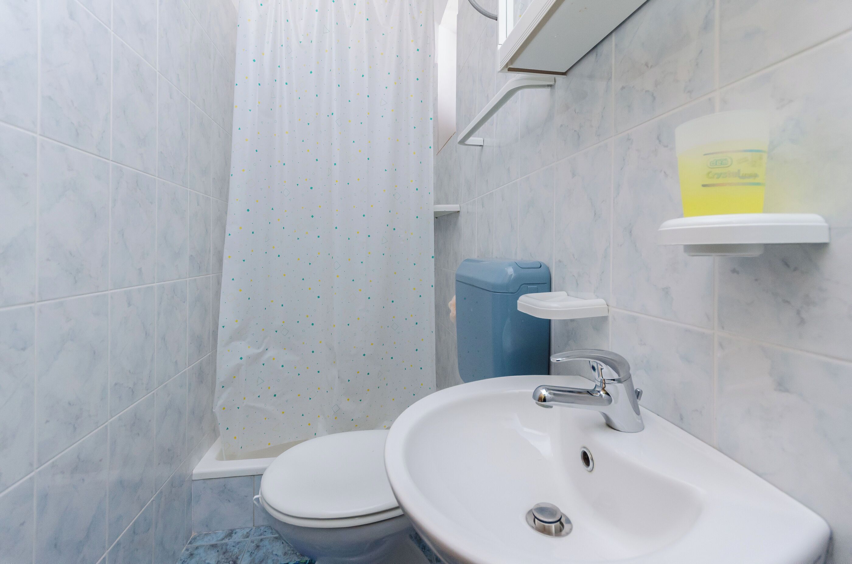 A bathroom with a toilet, sink, and shower curtain.