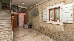 A stone-walled interior with a staircase, a wooden door, and a window with curtains. - Apartments Cash and Dash (Krilo Jesenice)