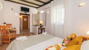 A hotel room with two beds, a desk with a chair, a small table with a phone, and a mirror.