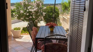 Eine Außenpatio mit Tisch und Stühlen, einem großen Sonnenschirm und Blick auf ein Gewässer und Grünflächen.