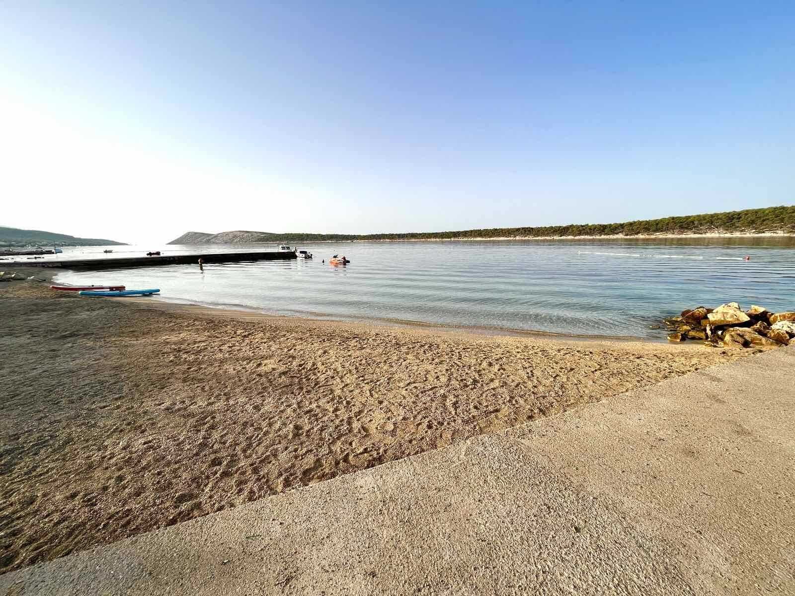 Uma praia com barcos, uma área rochosa e céu claro.
