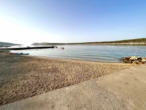 Een strand met boten, een rotsachtig gebied en een heldere lucht.