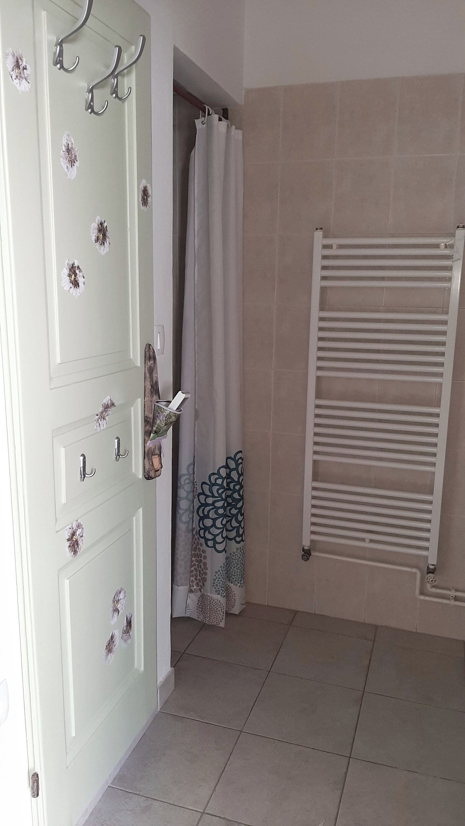 A bathroom with a white door, a towel rack, a shower curtain, and a towel rack with folded towels.