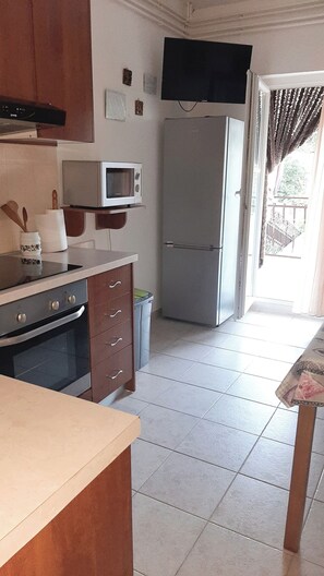Eine Küche mit Mikrowelle, Backofen, Kühlschrank und einem Fenster mit Vorhängen.