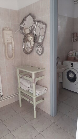 Ein Badezimmer mit Toilette, einer Waschmaschine und einem Regal mit gefalteten Handtüchern.