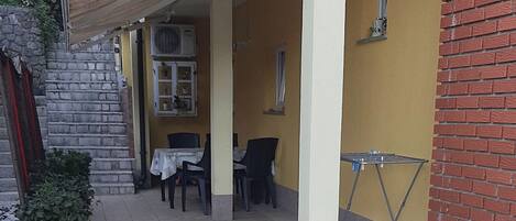 Un espacio al aire libre cubierto con suelo de baldosas, una mesa, sillas y una planta en maceta.
