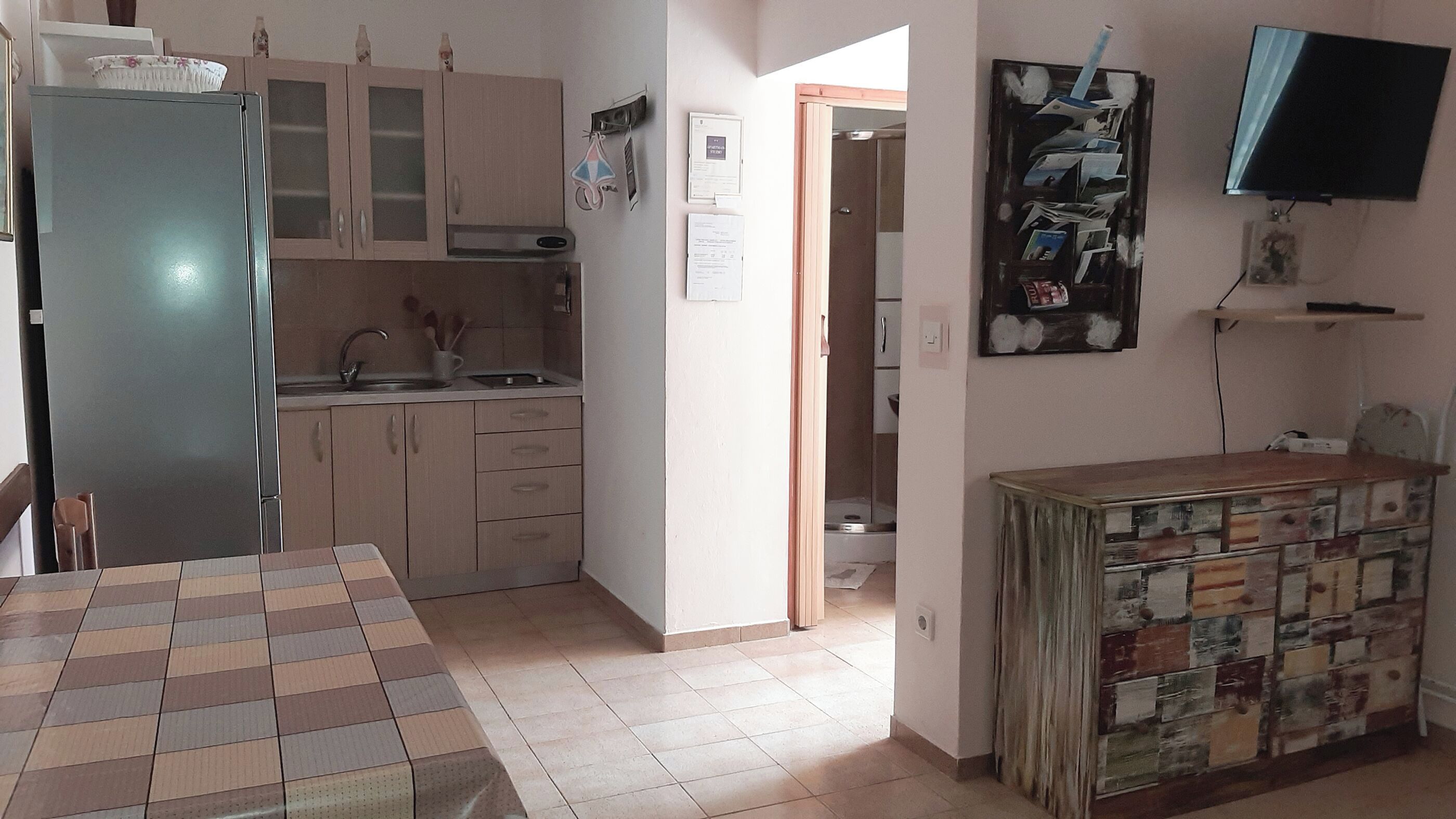 A kitchen with a refrigerator, cabinets, a sink, and a dining table.