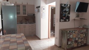 A kitchen with a refrigerator, cabinets, a sink, and a dining table. - Apartments Vesna (Moscenicka Draga)