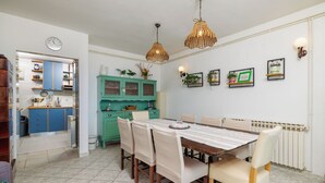 A dining area with a wooden table, chairs, and a kitchen in the background. - Apartment Aneta (Povile)