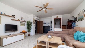 A living room with a TV, sofa, coffee table, and ceiling fan. - Apartment Aneta (Povile)