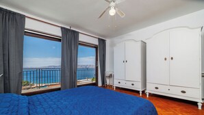 A bedroom with a bed, a wardrobe, and a view of the sea. - Apartment Aneta (Povile)