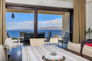 Un balcone con vista sul mare, un tavolo da pranzo con sedie e un divano.
