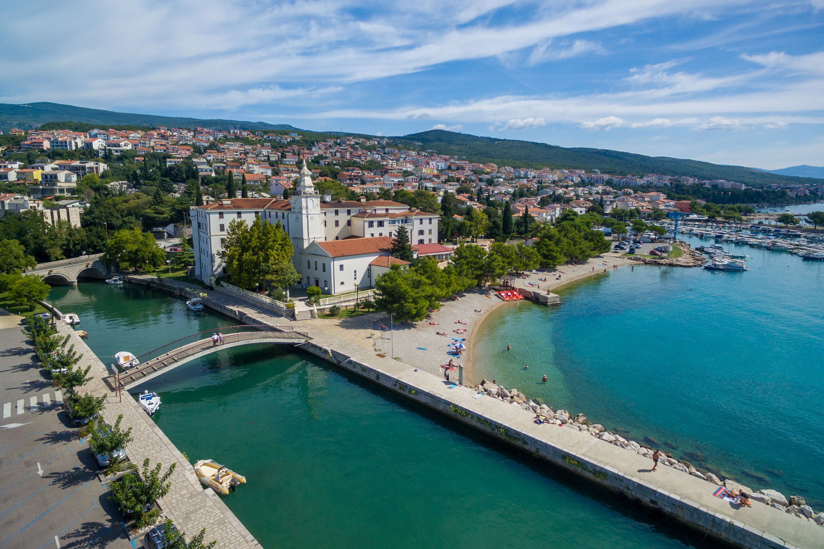 A coastal town with a prominent church, a marina, and a beach area.