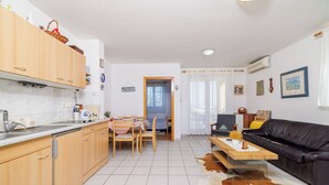 Eine moderne Küche mit Holzschränken, ein Essbereich mit Tisch und Stühlen, eine schwarze Ledersofa und ein Kuhfellteppich.