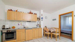 Eine kompakte Küche mit Holzausstattung, einem eingebauten Backofen und einem Essbereich mit Tisch und Stühlen.