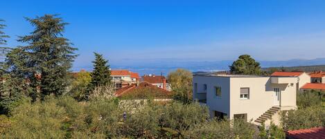A residential area with houses, a clear blue sky, and a distant view of the sea.