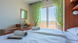 Una camera d'albergo con un letto, una scrivania, una sedia, un tavolino e una finestra con tende.