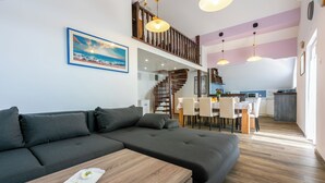 Un soggiorno moderno con un divano componibile, un tavolino in legno e una zona pranzo con una cucina sullo sfondo.