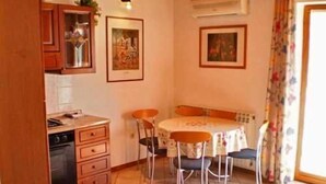 A compact kitchen with a dining area, featuring wooden cabinets, a stove, and a small table with chairs. - Apartment Anto (Umag)